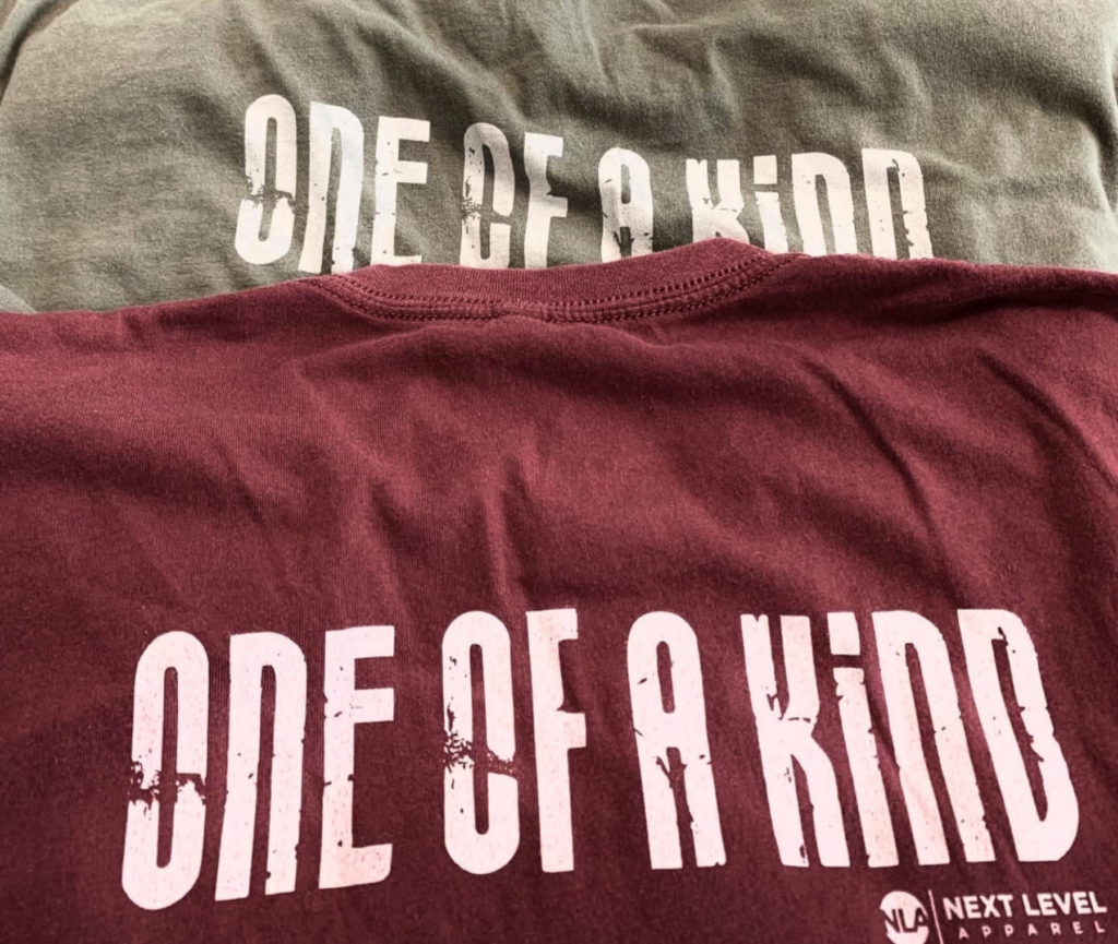 Two t-shirts with “One of a Kind” printed design in different colors.
