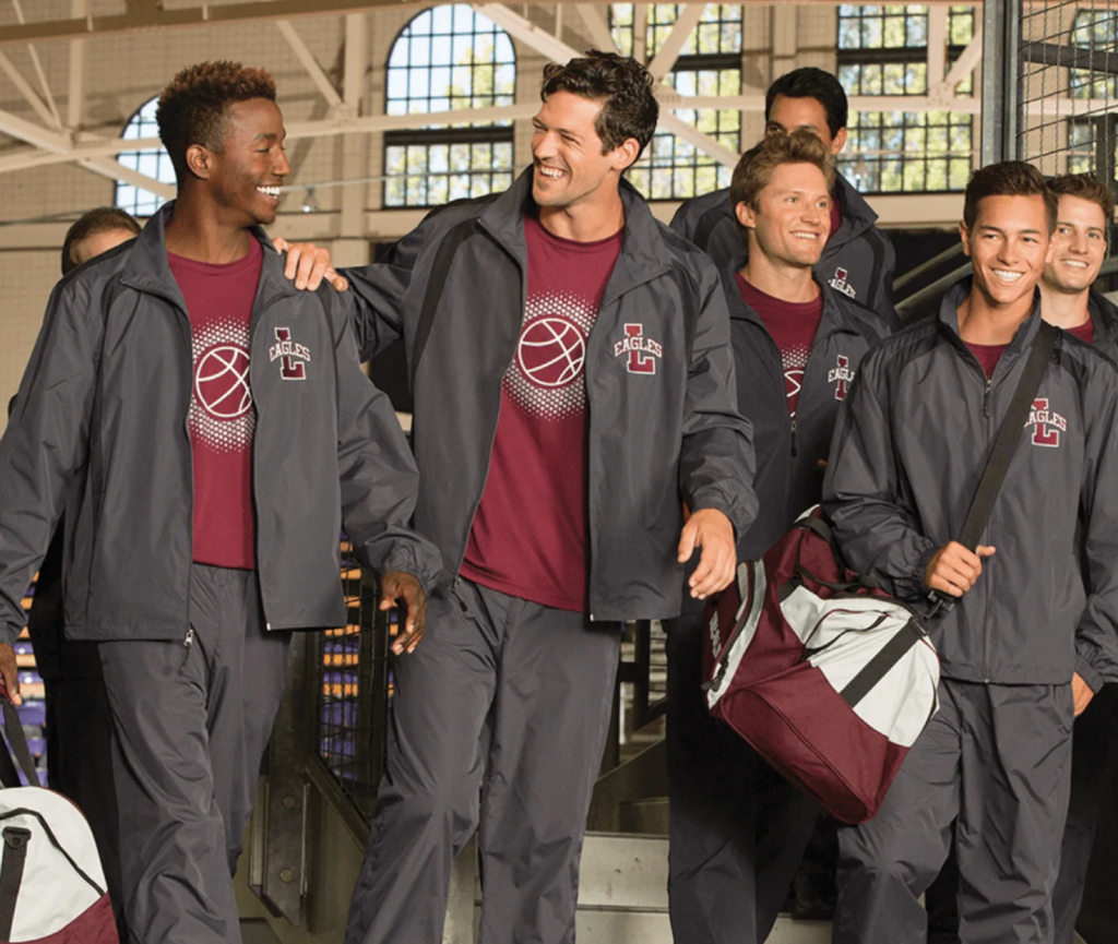 Group of athletes wearing matching team jackets and shirts walking together indoors.