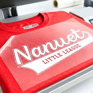 Red T-shirt with heat transfer logo being applied, suitable for custom team apparel